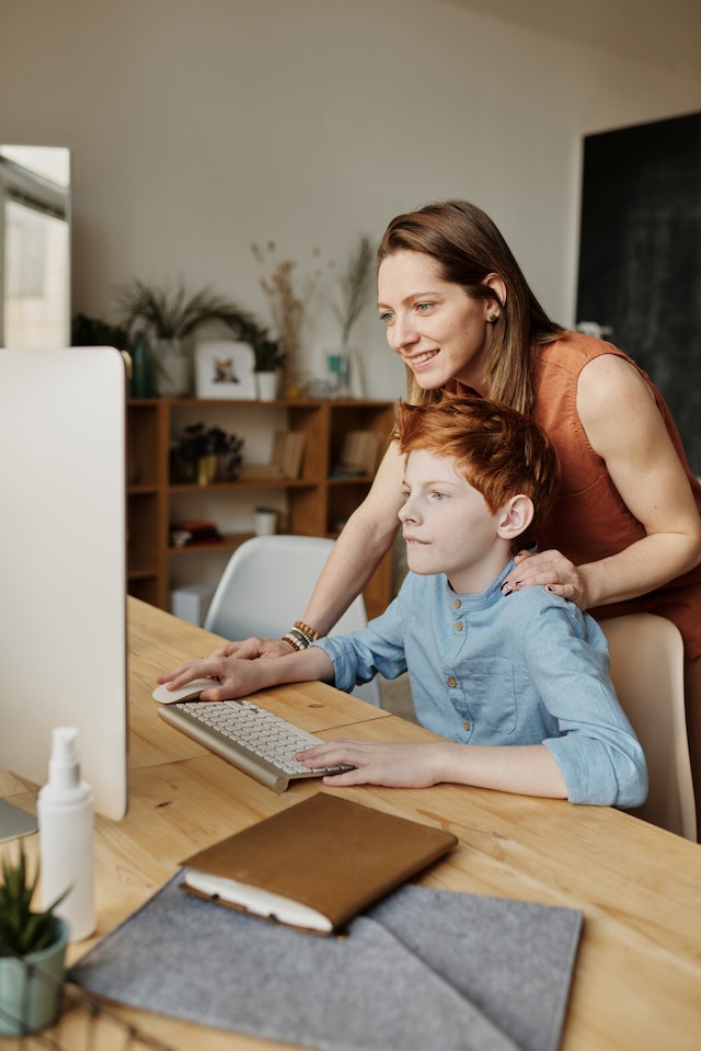A mother and her son preparing for an online intelligence test at a computer. 